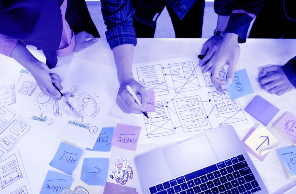 UX designers create a design on a desk full of notes